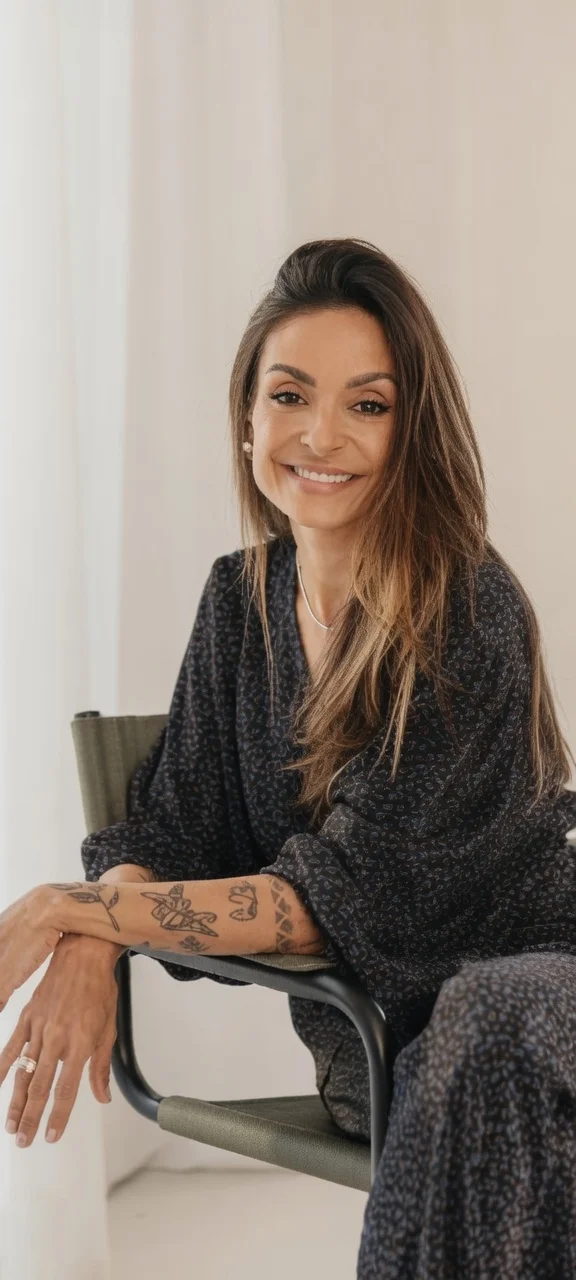 Dra. Claudia Cogo sorrindo, sentada em uma poltrona